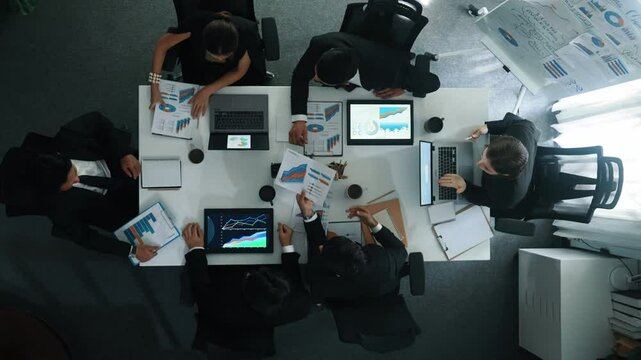 Top view of businesswoman sit at seat and start to analyze stock market data with diverse business team at meeting table with marketing chart document and tablet display financial report. Directorate.