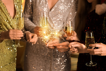 Beautiful women with champagne and Christmas sparklers at Christmas party, closeup