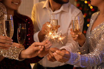 People with champagne and Christmas sparklers at party, closeup © Pixel-Shot
