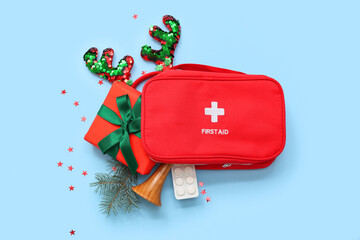 First aid kit with Christmas gift on blue background