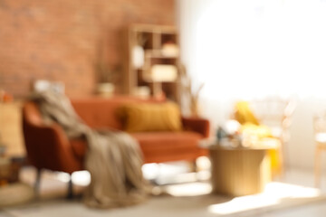 Blurred view of living room with red sofa, armchair and pumpkins