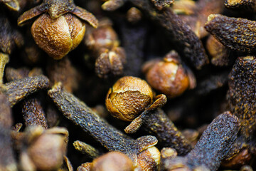 A close-up texture of freshly dried clove spices scattered on the ground. Cloves serve as a dried herb for food flavoring and natural medicine. Dry Organic Clove Spice.