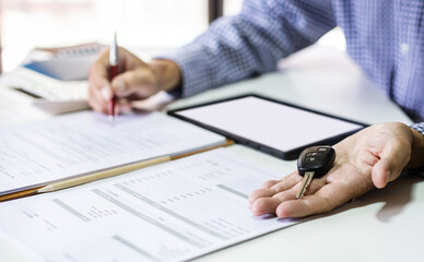 Men's hand holding car key reviewing personal loan contract and car accident insurance calculate monthly installments before making an agreement about contract to apply for a car loan, Close-up shot
