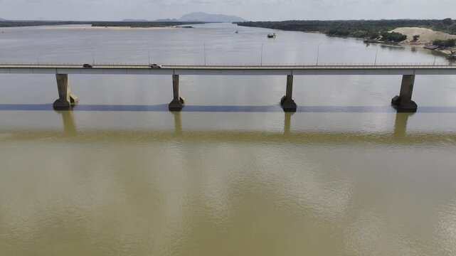 Drone flies backwards over Rio Branco river from Ponte do Macuxis bridge in Boa Vista, Roraima, Brazil