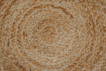 Textured natural woven round mat with spiral patterns on a neutral background