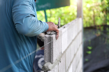 masonry worker make concrete wall by cement block and plaster at construction site      