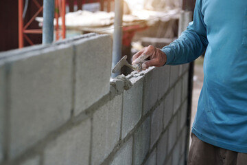 masonry worker make concrete wall by cement block and plaster at construction site      