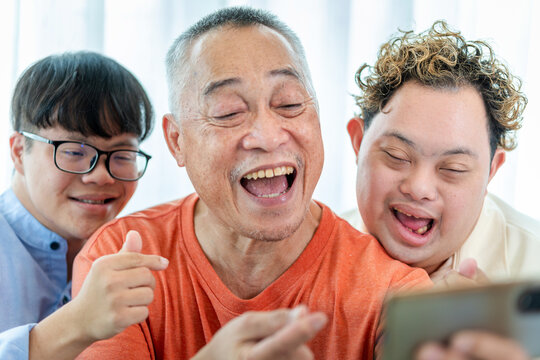 Senior man and grandchild using smartphone take selfie, Cheerful grandfather relaxing with grandchild and friends in living room