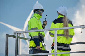 Maintenance engineer team standing at windmills at wind turbine farm. Group of people wear safety...
