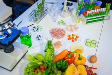 A detailed research concept in laboratory table setting, focused on food ingredients vegetables and meat. Test tubes, microscopes, lab equipment used to analyze nutritional extracts and vitamins.