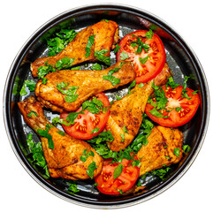 Deliciously seasoned chicken legs with tomatoes and parsley in a black pan