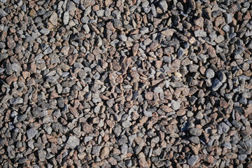 Close-up of gravel showing diverse stone sizes and shades on a sunny day at a construction site