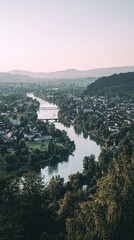 Fototapeta premium A serene view of a river flowing through a picturesque town, surrounded by lush greenery and mountains in the distance.