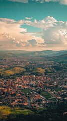 Obraz premium Aerial view of a vibrant city surrounded by lush hills under a clear sky, showcasing urban life and nature's beauty.