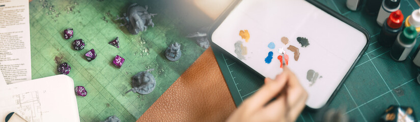 Hand using brush paint acrylic colour to miniatures for tabletop role playing game and fantasy...