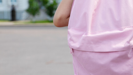 Little girl with pink backpack going to school outdoors, back view