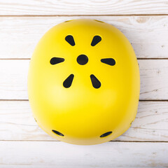 Yellow helmet on wooden background. Child's outdoors activity safety protection: rollers, bicycle, skateboard.