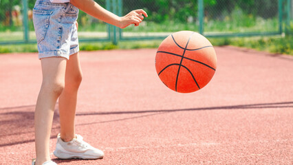 Naklejka premium Child girl practicing exercise hitting basketball ball training on court in city.