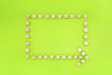 黄緑の背景でウッドキューブを左回りの四角い矢印に並べたフレーム