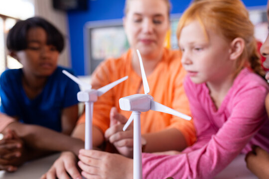 In school, diverse children learning about wind turbines with female teacher in classroom