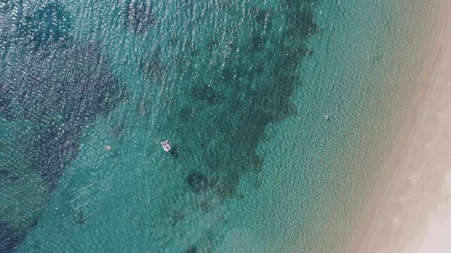 Aerial top down shot of a twin double beach on the Greek island of Kythnos, part of the Cyclades islands complex. Flying sideways to reveal swimmers and the amazing beach with crustall clear waters.