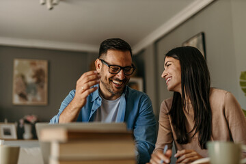 Happy family couple managing household budget, planning investment, analyzing paper utility bills, making payments and fill application forms together