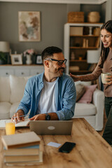 Man doing freelance work and getting a coffee from his wife