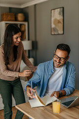 Adult man work from home while his wife hug and stand with him