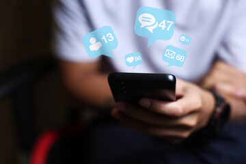 Close-up of man's hand using smartphone to play social media with emoticons or notifications popup.