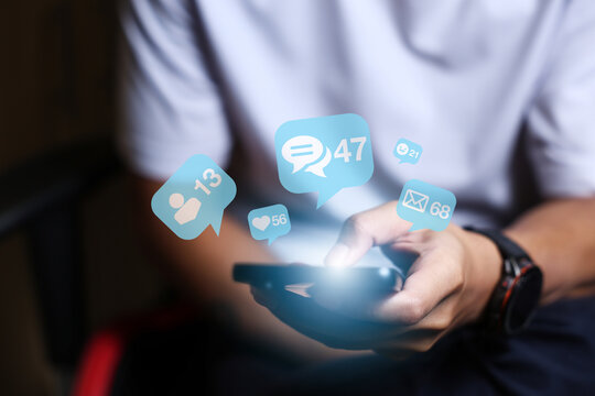 Close-up of man's hand using smartphone to play social media with emoticons or notifications popup.