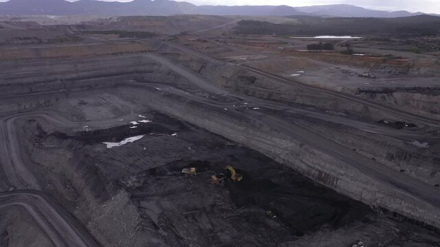 Aerial view of a large open-pit coal mine with an excavator loading a truck in the Hunter Valley, NSW, Australia