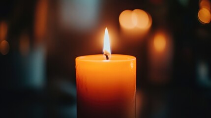 A close-up of a burning candle with an orange flame flickering in the dark, creating a cozy and warm atmosphere.