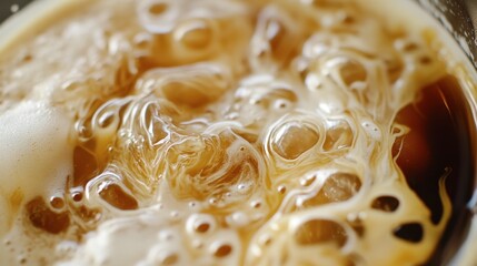 A close-up of a cup of Vietnamese iced coffee with condensed milk swirling in the dark brew.