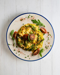Scrambled organic chicken eggs with green asparagus and tomato. Top view table with  decoration.