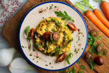Scrambled organic chicken eggs with green asparagus and tomato. Top view table with  decoration.