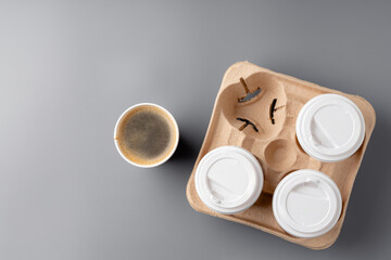 Warm coffee in a brown paper cup on a gray surface with a tray