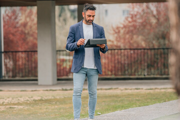 attractive businessman on the street with tablet or laptop