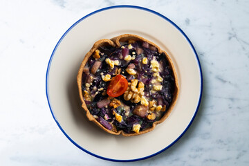 Individual vegan quiche with vegetables and red cabbage. Top view table with  decoration.