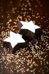 Christmas cookies (cinnamon stars) and brown sugar on dark background. Close up.