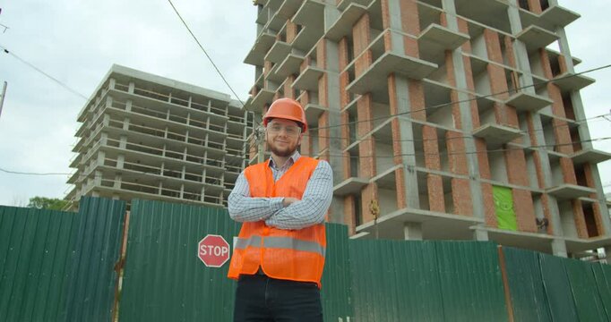 Portrait of male builders engineers contractor worker foreman architect in hard hat on background of building under construction looking at camera.