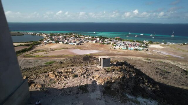 Lighthouse on a rocky hill overlooking a coastal village and turquoise sea in Los Roques, Venezuela
