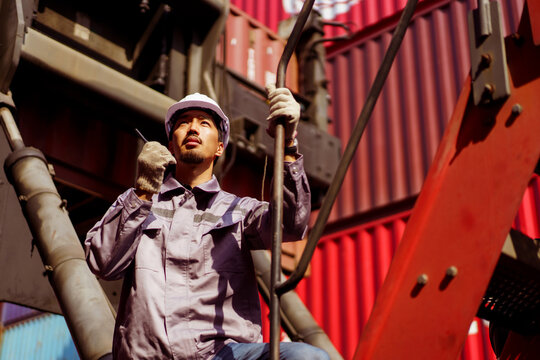 Asian male container yard worker perform an inspection.