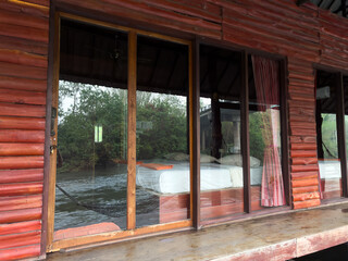 A wooden cabin with a large window overlooking a river