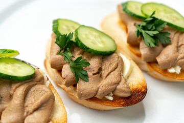 Savory canapes topped with creamy spread and cucumber slices served on toasted bread at a casual gathering