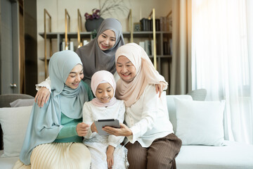 Happy multi-generation family using a digital tablet on the sofa in a living room at home