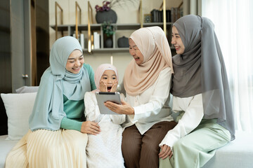 Happy multi-generation family using a digital tablet on the sofa in a living room at home