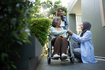 Senior female patient in wheelchair with her daughter and female doctor in hospital