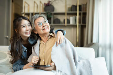 Daughter taking care of her mother by cover with blanket in a living room at home