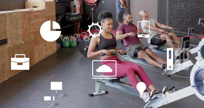 Image of business icons over diverse people using indoor rower on gym - Powered by Adobe