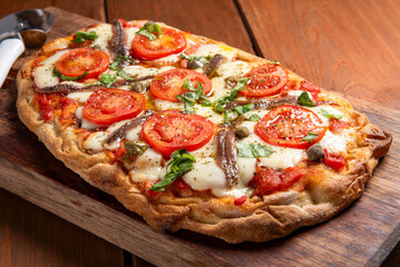 Pinsa romana con mozzarella, pomodoro fresco e acciughe, cibo italiano 